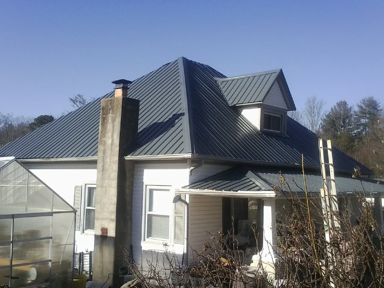 Dark blue standing seam metal roof on a white farmhouse with dormer — Slate & Tile Roof Repair by Roofing Brothers in Rancho Cordova