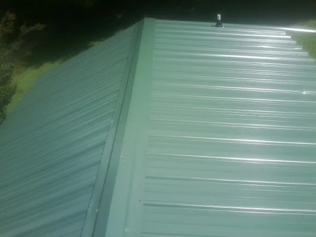 New green metal panels meeting at the ridge of a roof — Flat Roof Repair work by our crew in Rancho Cordova