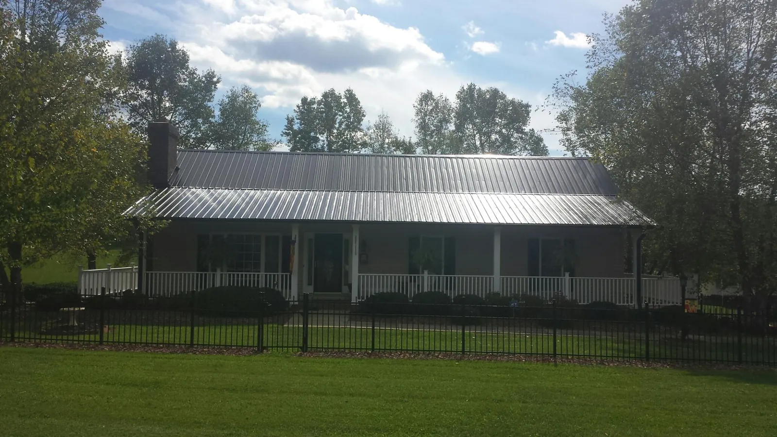 Gray metal roof on a brick ranch with a full width front porch — Gutter Guard Installation work by our crew in Rancho Cordova