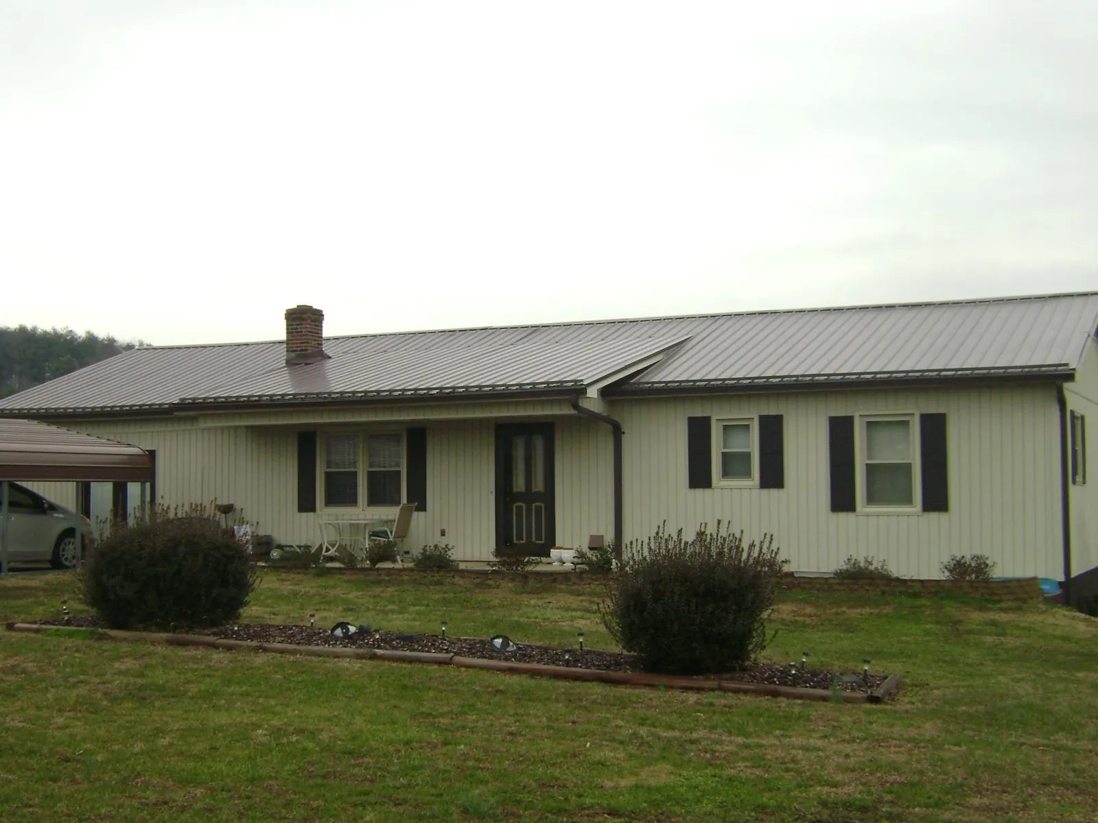 Brown metal roof on a cream sided ranch home with a brick chimney in Rancho Cordova