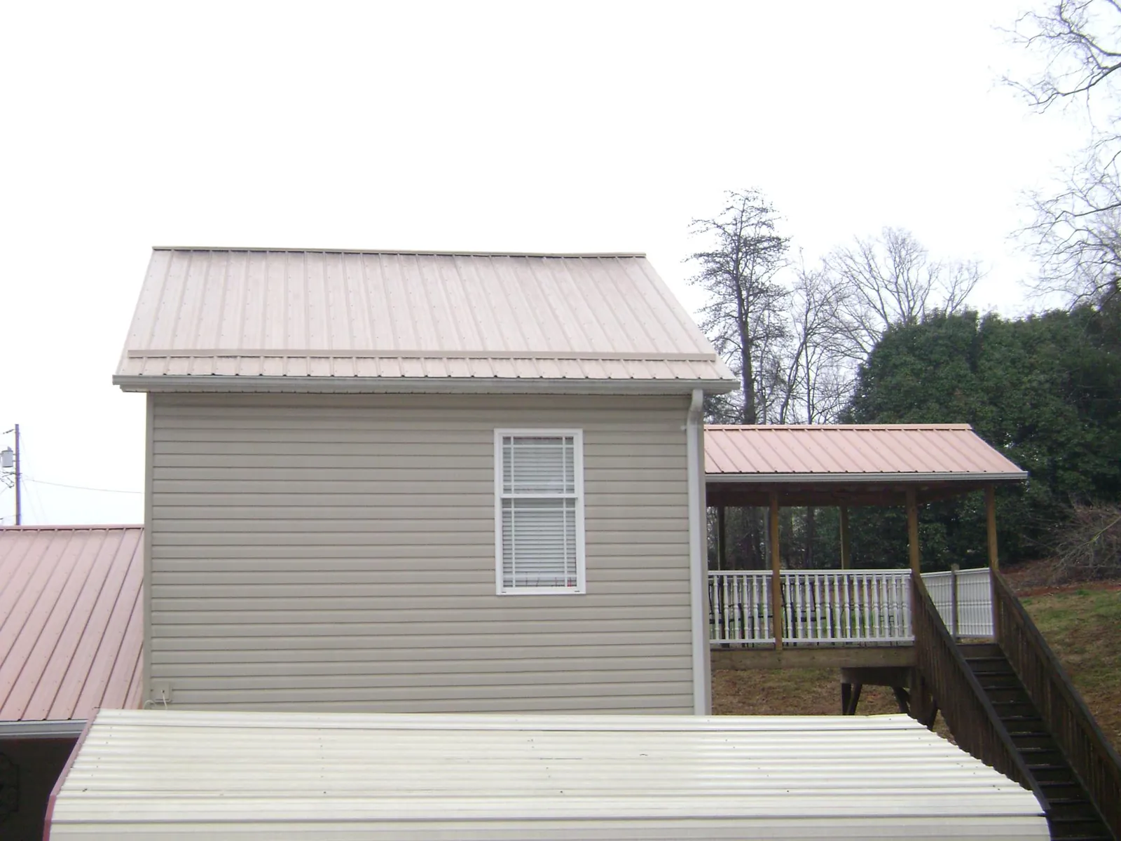 Tan metal roofs on a two story addition and attached porch, from a Roof Replacement job in Rancho Cordova
