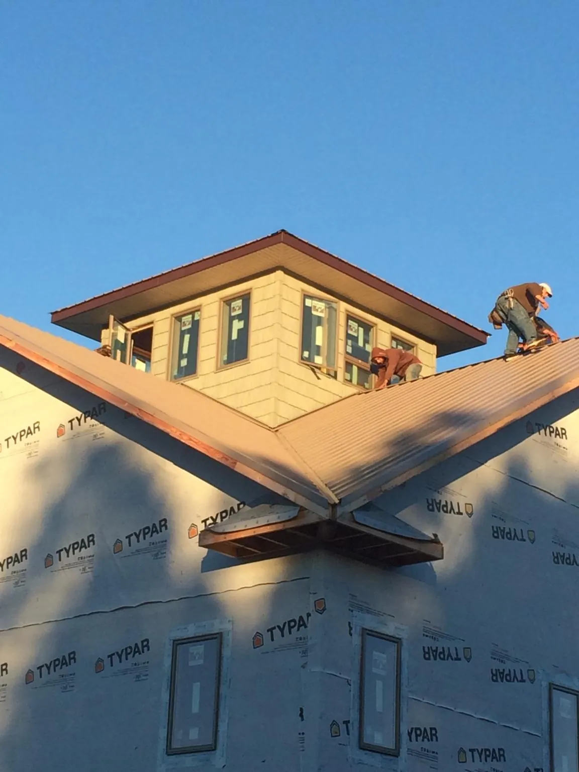 Roofers working around a rooftop cupola on a new metal roof at sunset — Roof Waterproofing in Rancho Cordova by Roofing Brothers